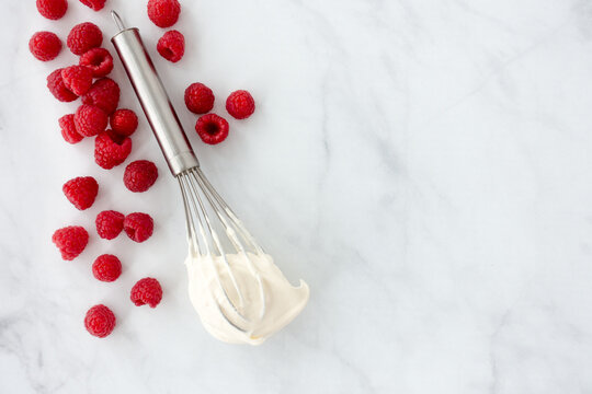 Raspberries and a Whisk with Whipped Cream on Marble Background