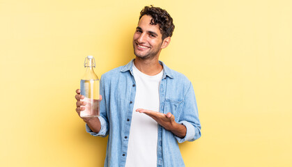hispanic handsome man smiling cheerfully, feeling happy and showing a concept. water bottle concept