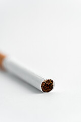 Single cigarette on white background. Copy Space. Close up.