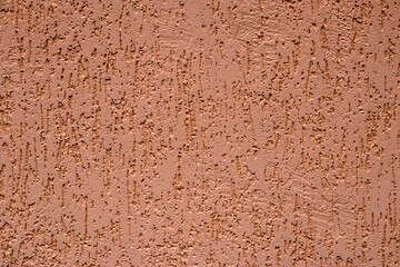 Simple textured finish of facade of building. In form of uneven scratches. Construction texture of peach colored. Inexpensive original finishing of facades with wet plaster