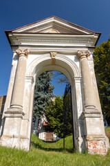Fototapeta premium Classicist gate at the entrance to a country cemetery with a baroque chapel