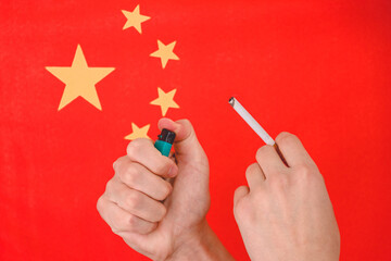 Hand and cigarette on the background of the flag of china.