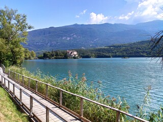 Fototapeta na wymiar Promenade along Lake Toblino with Toblino Castle in the background, in Madruzzo, Trentino Alto Adige 