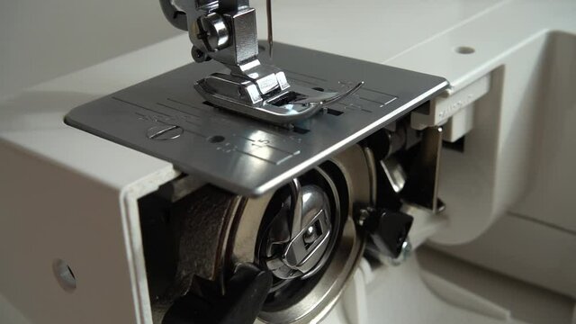 The needle of a sewing machine makes a thread stitch. Slow motion. Elements of the sewing machine mechanism at work. Internal parts of a sewing machine. 