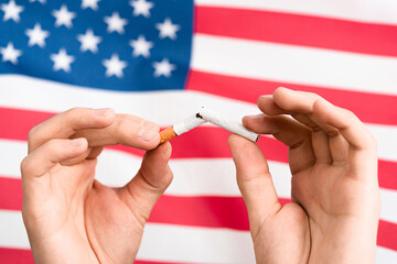 Hand and cigarettes on the flag USA. Hand breaks