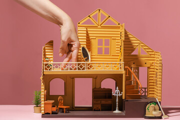 A toy house and a hand depicts a little man. A happy buyer of his own house, his own home, a funny...
