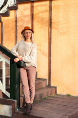 Obraz premium Young beautiful blonde woman in sweater and fedora felt hat, stands against yellow wall. Copy space and place for text