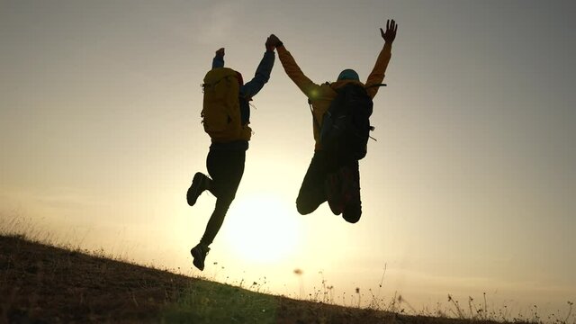 business teamwork a freedom concept. couple of tourists run with silhouette backpacks running jumping. travel freedom business concept. couple teamwork hikers running sunset jumping