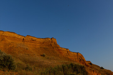 Fototapeta premium Geology. Desert landscape. Panorama view of the sandstone formation, the rocky cliffs, sand. Background or texture of sandy cliff on the coast, orange limestone