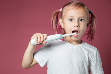 Smiling caucasian little girl cleaning his teeth with electric sonic toothbrush