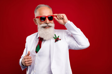 Photo of positive happy charming old man look empty space wear sunglass xmas isolated on red color background