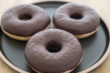 chocolate donuts on a black plate, pastries are sweet