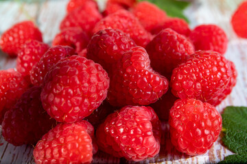 A handful of scarlet ripe raspberries on the old wooden table.