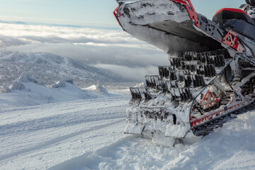 a caterpillar of a sports snowmobile in close-up against the background of a mountain valley. the concept of recreation on a mountain snowmobile in winter. snow bike rear view in detail