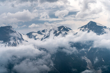 Fototapeta na wymiar Mountains Peaks above Clouds and Fog at Grossglockner Iceberg in Austria Alps