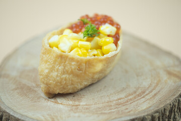Fried tofu stuffed with rice and topping with  fish roe and corn