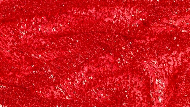 Abstract red background.Christmas background.Glitter background. Movement of the red fabric embroidered with sequins. Stop motion.