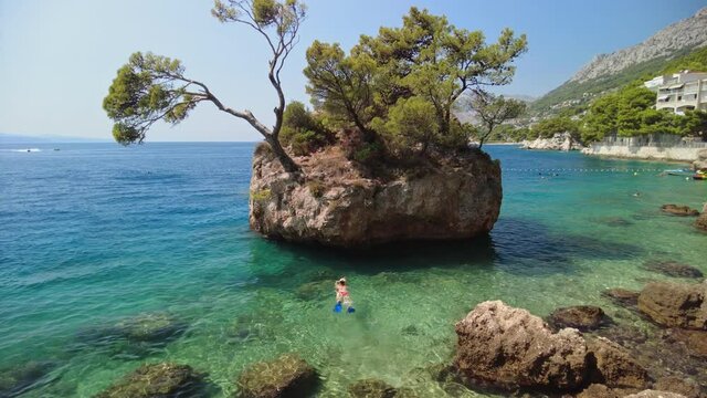 Woman in bikini, snorkeling in Punta Rata beach in Croatia around the famous Brela stone or Kamen Brela. Swimming in Croatian Adriatic Sea in the Split-Dalmatia County of Croatia in Europe.