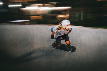 Man wearing helmet while skateboarding on sports ramp at night