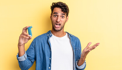 hispanic handsome man feeling extremely shocked and surprised. asthma concept
