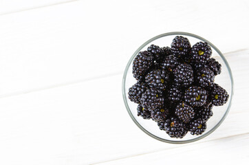 Fresh ripe blackberries in bowls on white wooden table, flat lay