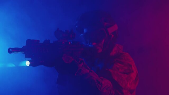 Woman soldier in uniform looks into the sight of rifle, lighting a blue-red studio with a flashlight. Concept of investigation.