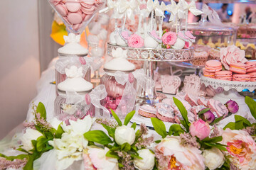 Delicious desserts at the wedding candy bar in the buffet area: cookies covered with icing, decorated with angels, cameo, sugar rosebuds and silver dye