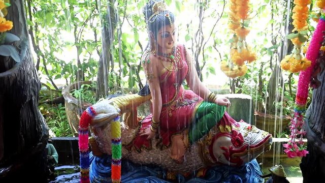 Phra Mae Thorani, goddess from Buddhist mythology, behind water of fountain.
