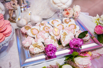 Delicious desserts at the wedding candy bar in the buffet area: cookies covered with icing, decorated with angels, cameo, sugar rosebuds and gold dye
