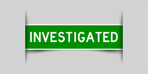 Inserted green color label sticker with word investigated on gray background