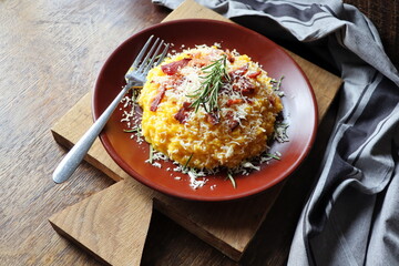 Risotto with pumpkin and bacon on a dark wooden table