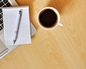 Laptop with coffee cup, notebook and pen on wooden background, concept for home office. Business concept. Work from home. desk office with laptop, blank notepad, coffee cup and pen on wooden table.