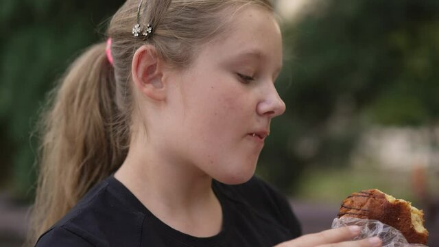 Fat girl eating s bun at the street