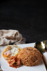 Kimchi lettuce fried rice with fried egg in white plate on black background