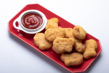 Chicken nuggets with tomato sauce in red plate