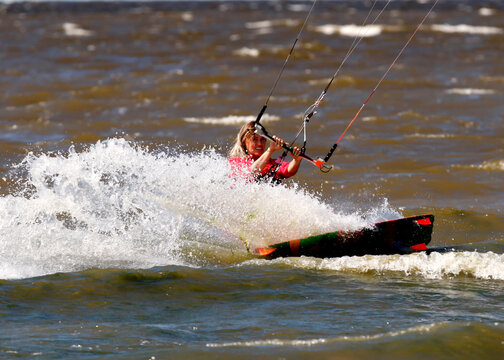 Kiter girl glides on sea waves
