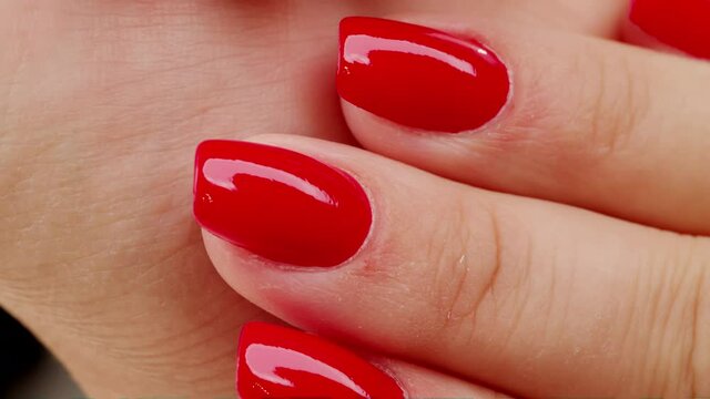 4K video of Female hands with fashionable manicure of red color . Woman shows her new red manicured nails, closeup. Beauty of nails. Classic red manicure.