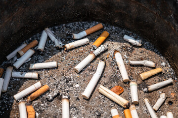 Group of cigarettes butt junk in ashtray, unhealthy concept seen. Close-up and selective focus at center part of the object.