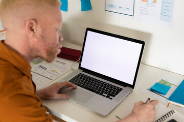 Albino african american man working from home using laptop with copy space - obrazy, fototapety, plakaty