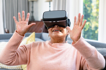 Happy mixed race senior woman wearing vr headset and having fun