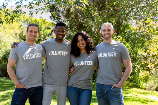 Group of smiling deverse female and male volunteers in matching tshirts looking at camera
