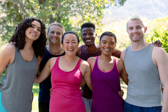 Group of happy fit diverse female and male friends holding yoga mats and taking selfie