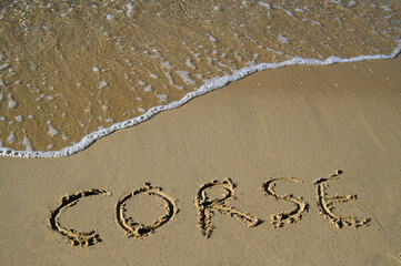 Corse écrit dans le sable d'une plage