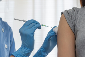 Covid-19,coronavirus hand of young woman nurse,doctor giving syringe vaccine, inject shot to asian...