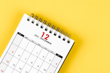 December 2021 desk calendar on yellow background.