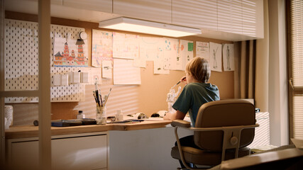 Little boy focused on work. Painting robot skeleton in his room