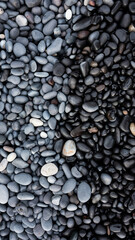 Fototapeta na wymiar Gray pebbles as a background in the Iceland sea shore. Abstract composition. Image for design and wallpaper on phone.