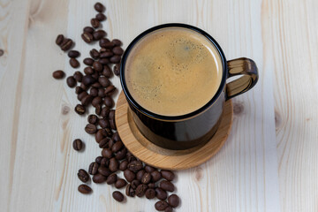 a cup of coffee on a wooden stand with a scattering of coffee beans