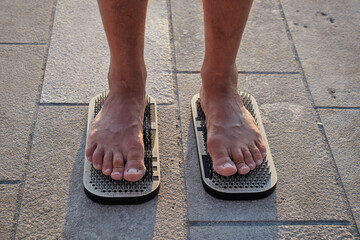 Male feet stand on a board with sharp nails. Sadhu's board. Practice yoga at dawn in the morning sun. Pain, trials, health, relaxation, cognition. Close-up