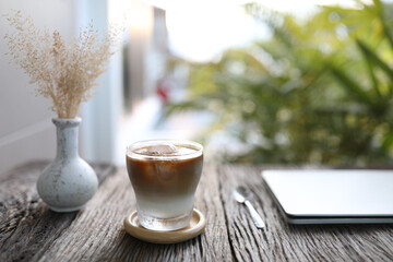 Ice coffee and dry grass flower on wooden table